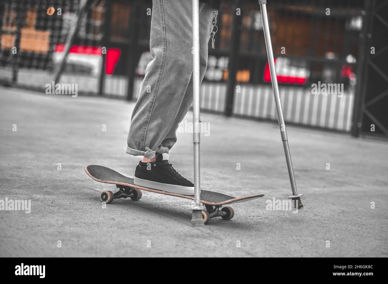 Legs of disabled guy with crutches sliding on skateboard Stock Photo