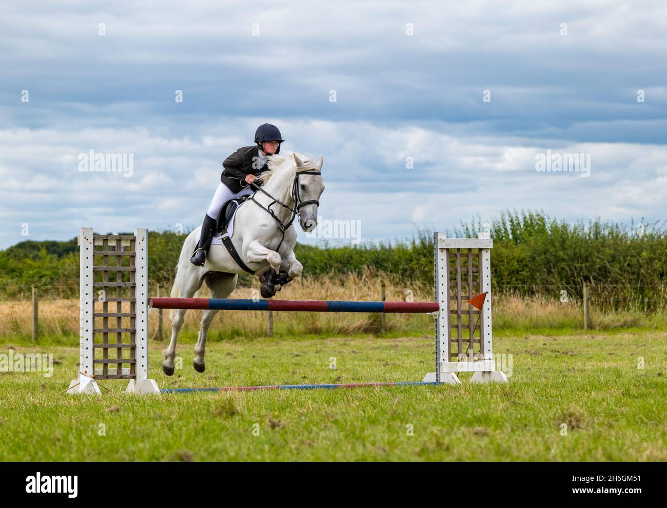 Summer horse show a boy riding a horse jumping over a horse jump, East