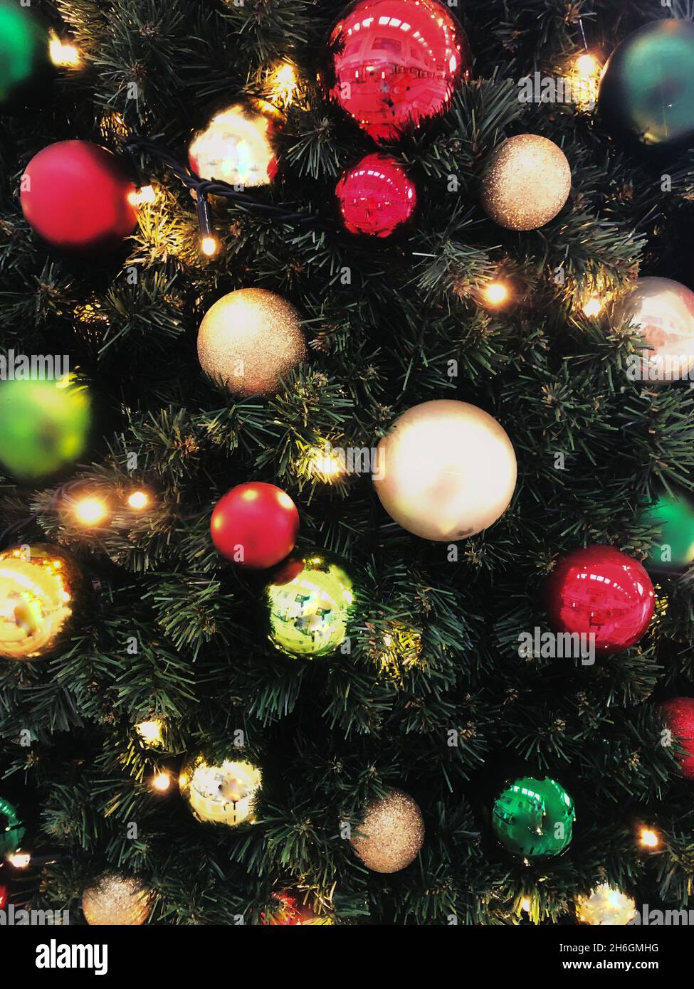 Full frame festive background of colourful Christmas baubles hanging on an artificial Christmas tree with copy space Stock Photo