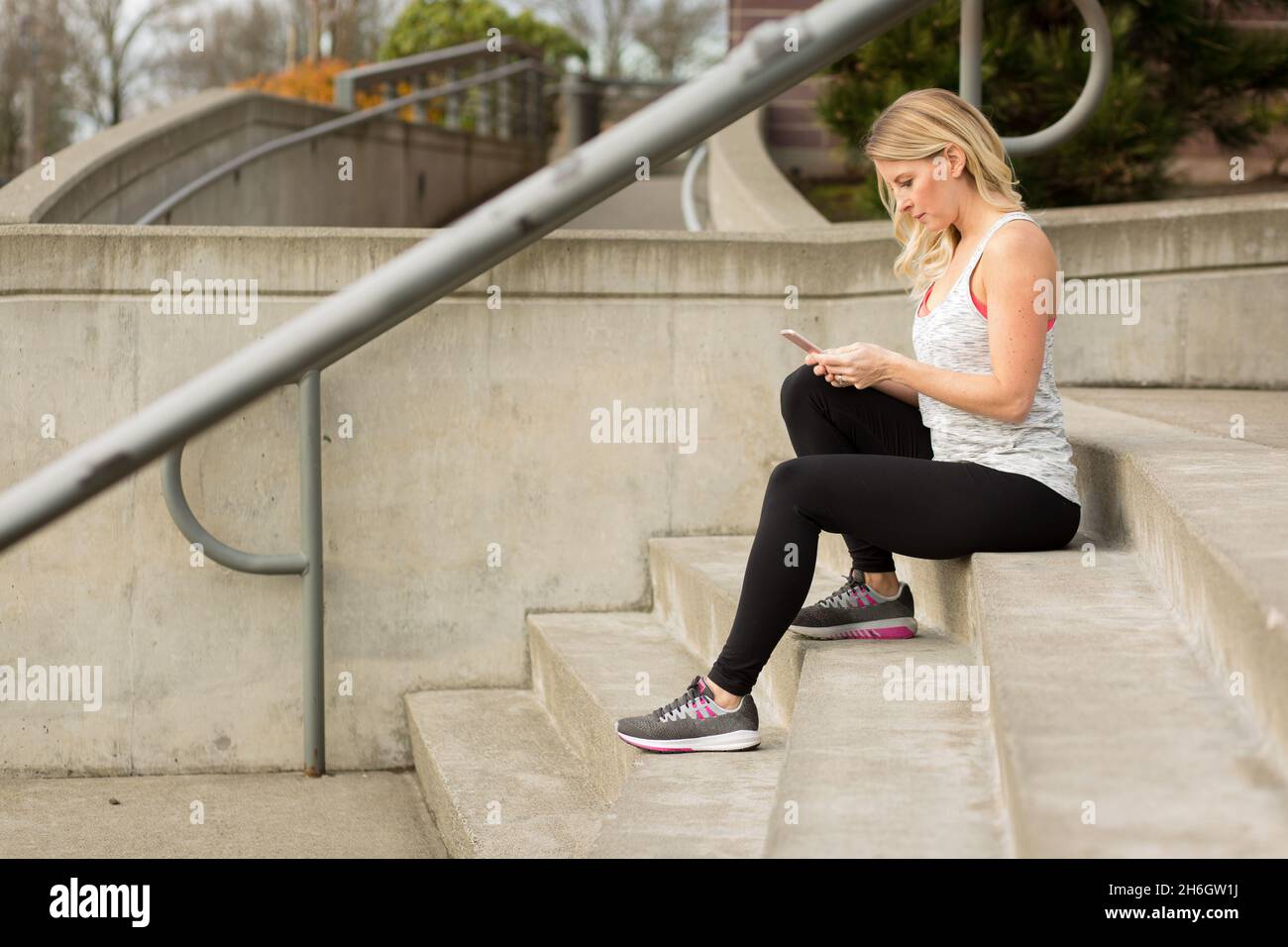 Attrractive woman in workout gear texting Stock Photo