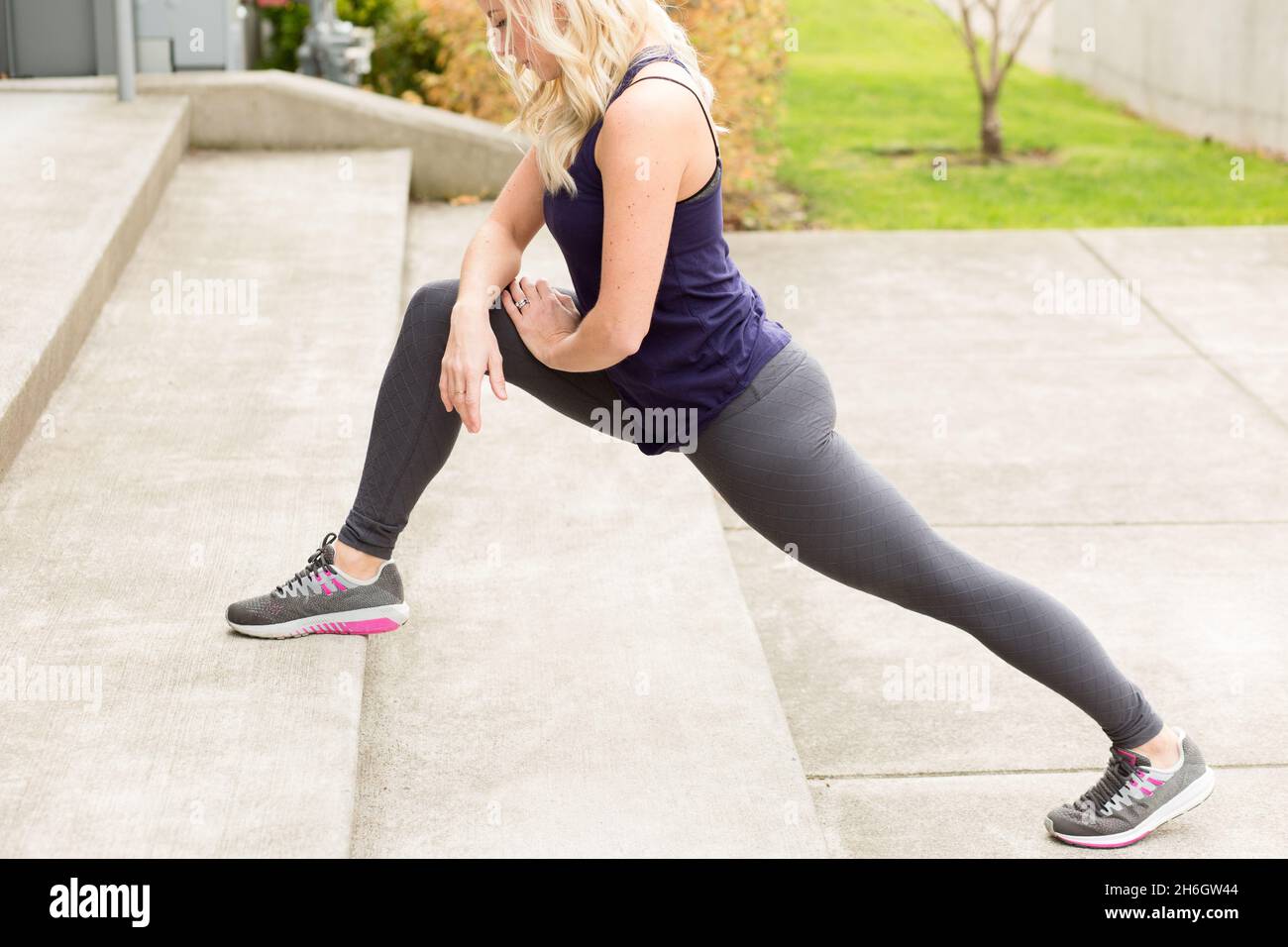 Closeup of woman stretching on concrete stairs Stock Photo