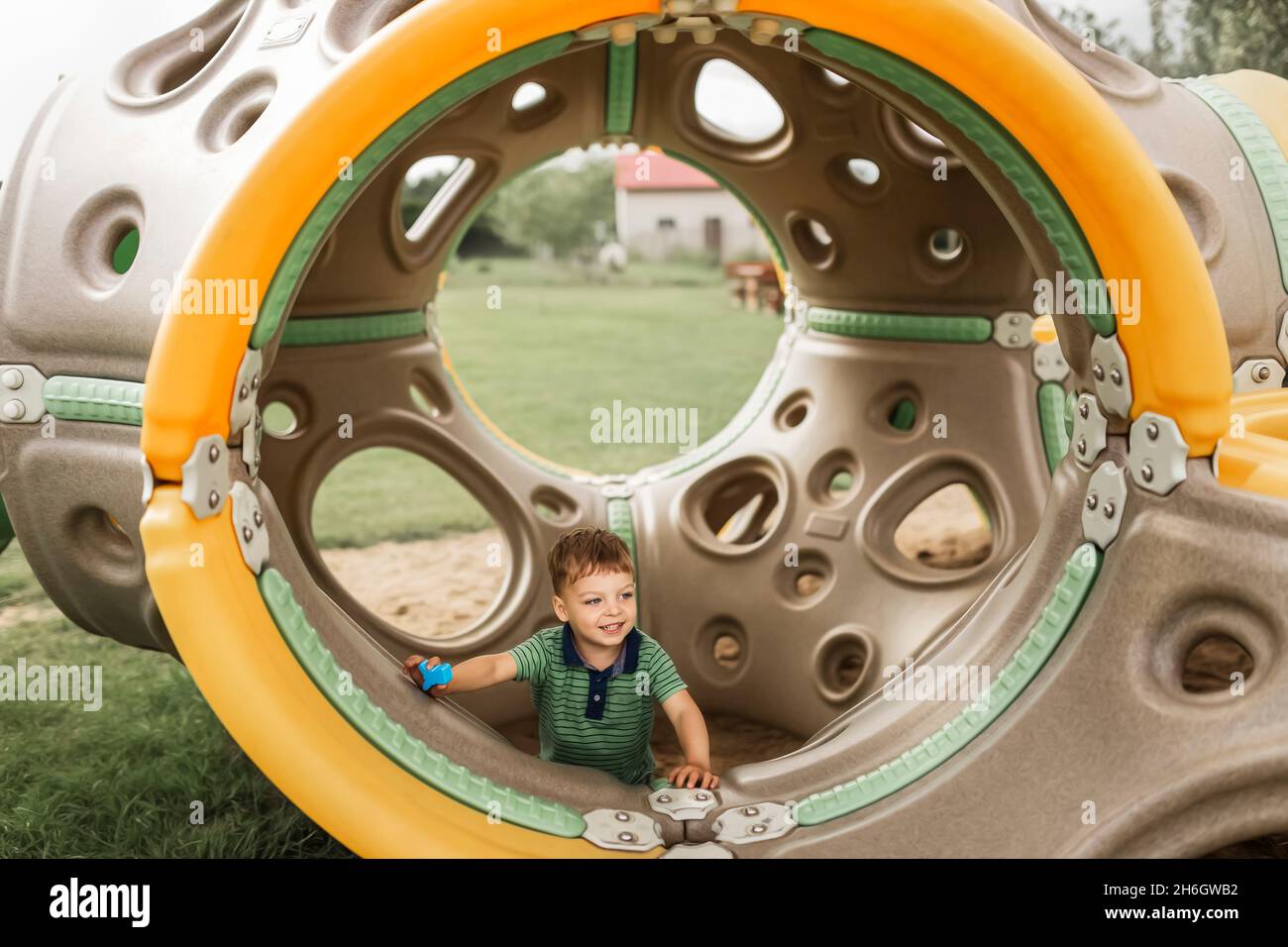 Blonde boy playing inside playground equipment Stock Photo