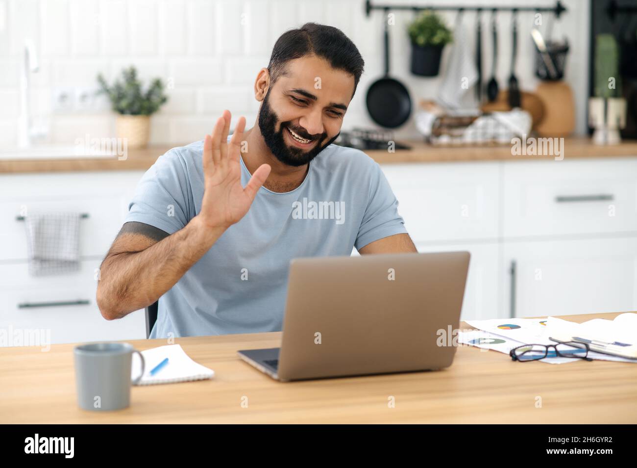 Online video communication. Positive successful Indian man, freelancer, designer or manager, work from home, using a laptop for communication via video call, talking to a colleague or friend, smiles Stock Photo