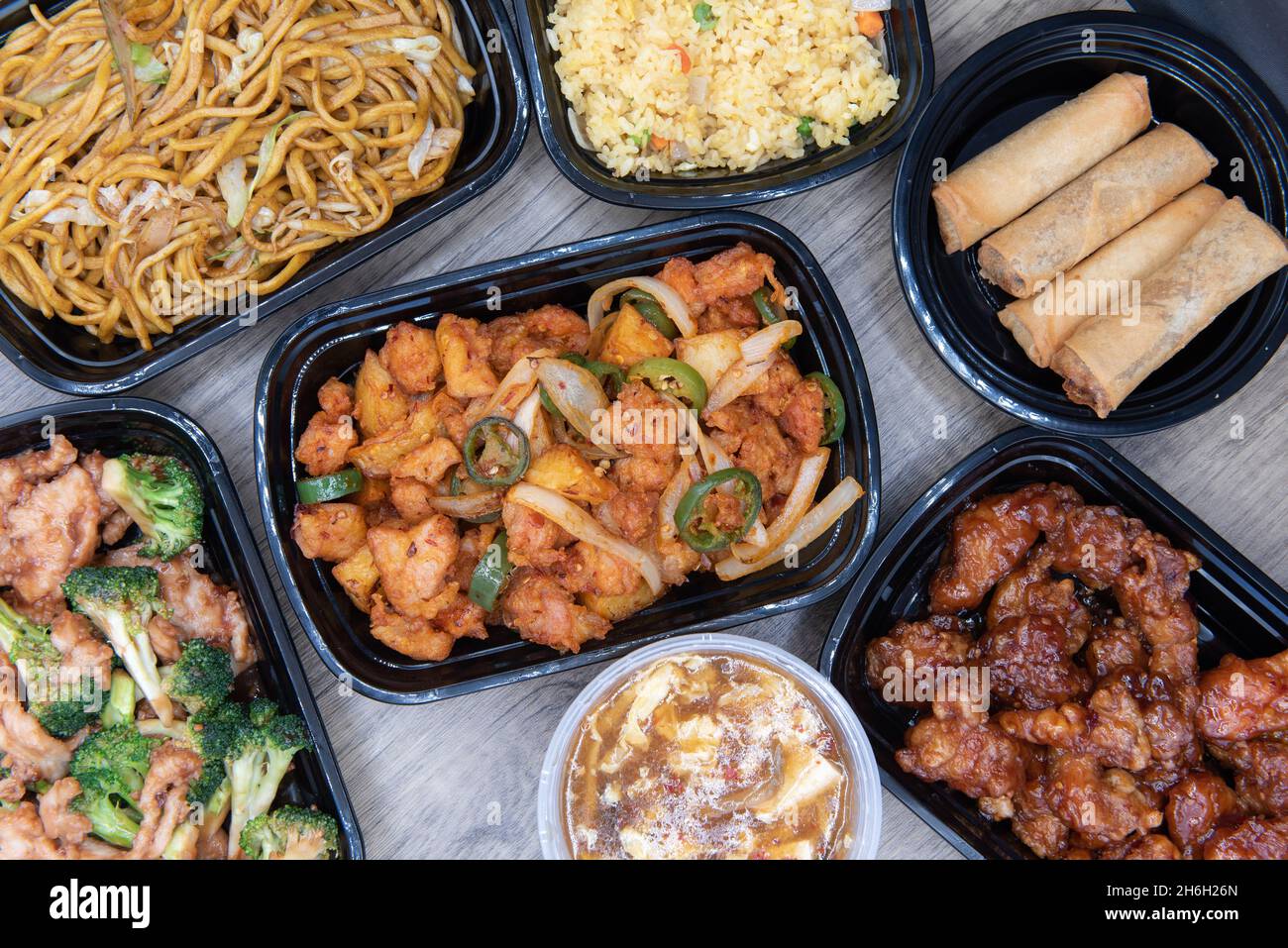 Overhead view of Chinese food feast is on the table buffet style with seasoned potatoes, orange chickn, curry chicken, shrimp, and fried rice. Stock Photo