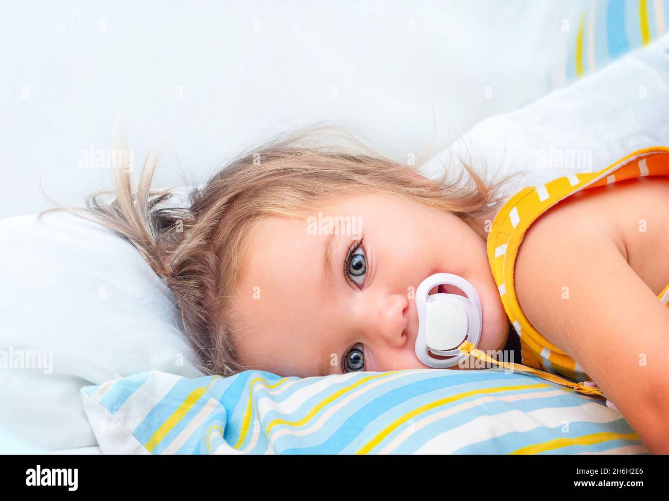 Cute baby with pacifier lies on the bed and smiles Stock Photo Alamy