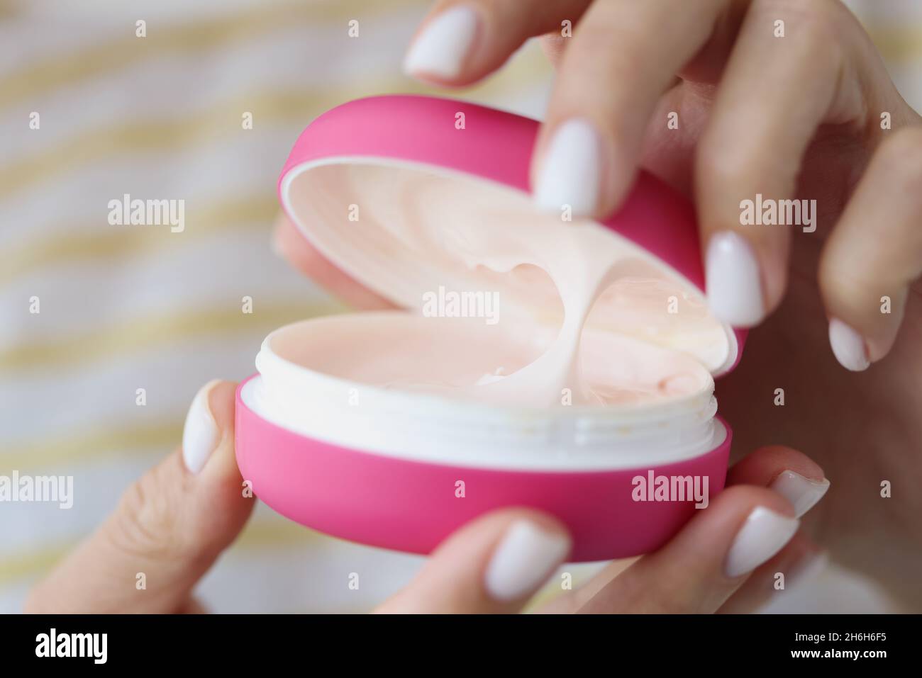 Lady open pink container with creamy texture inside for skin care Stock Photo