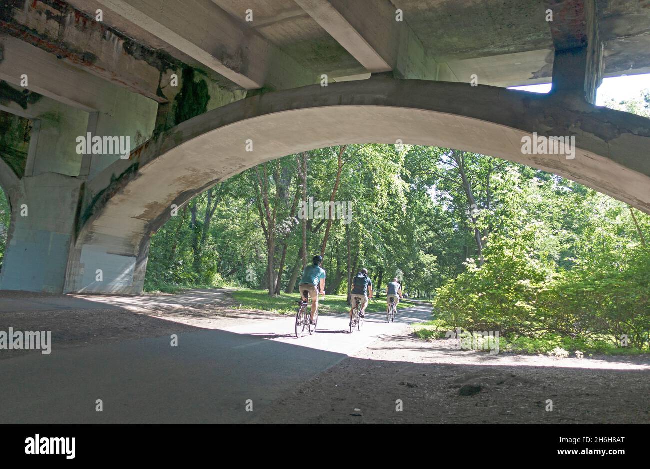Three men bicycling on the Minnehaha Creek Path under the Nicollet Avenue Bridge. Minneapolis Minnesota MN USA Stock Photo
