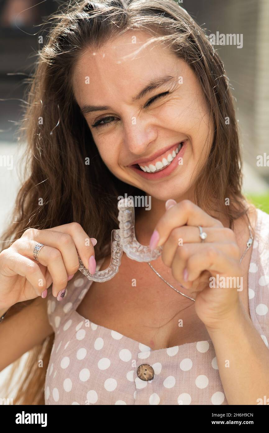 Beautiful caucasian woman holding transparent mouth guards for bite