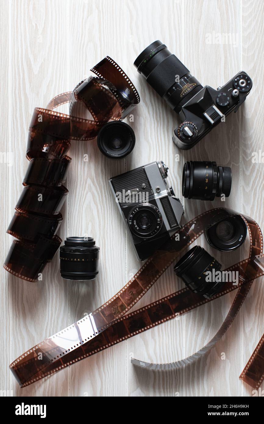 Film old cameras with lenses and manifested film on a white wooden