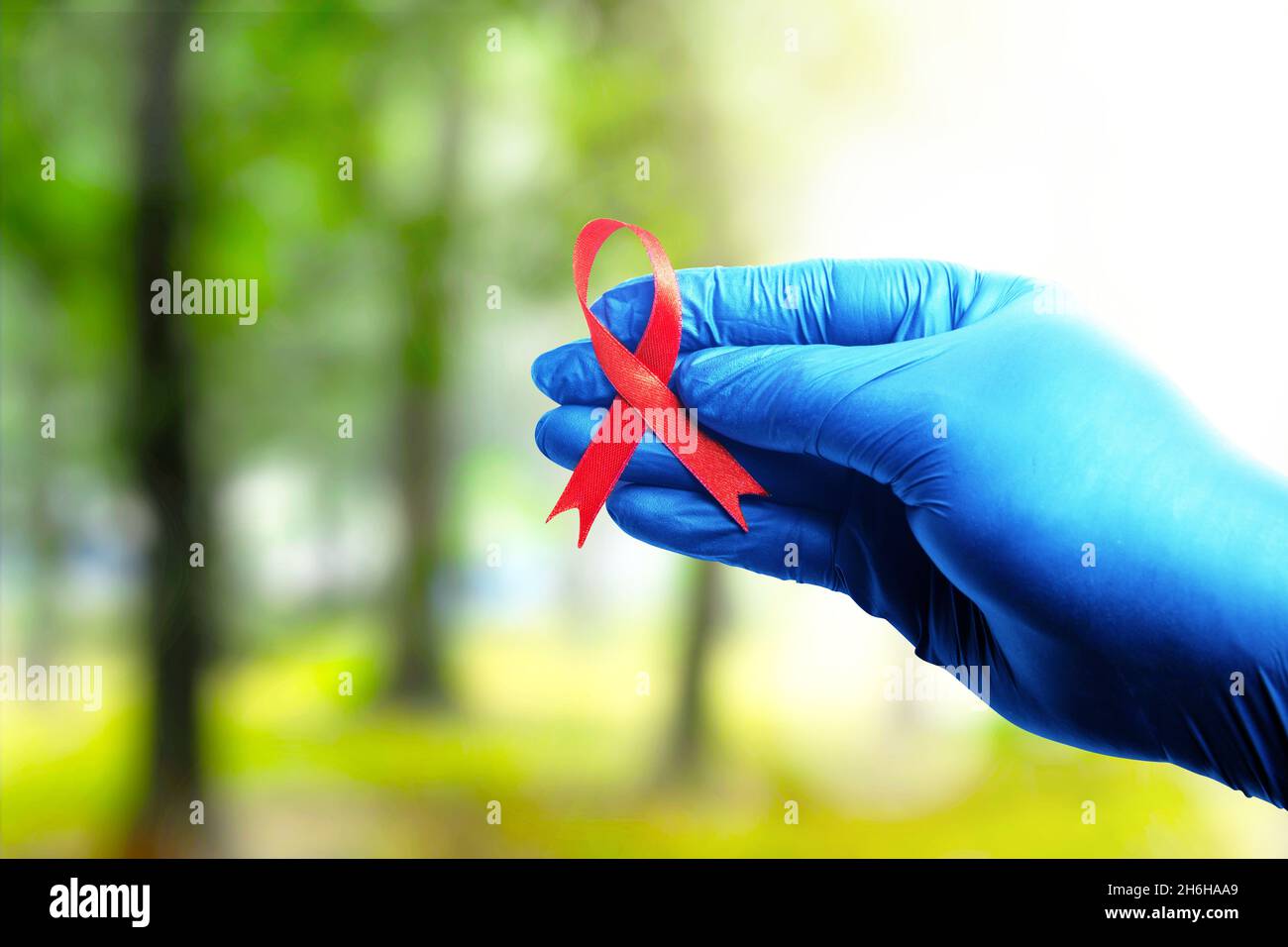 Red ribbon and medical glove with a bright background. Hiv Aids ribbon