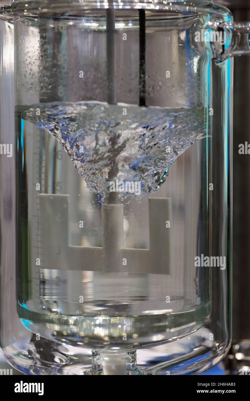 Mixing of liquid by an agitator with anchor blades. Laboratory glass reactor with stirrer. Selective focus. Stock Photo
