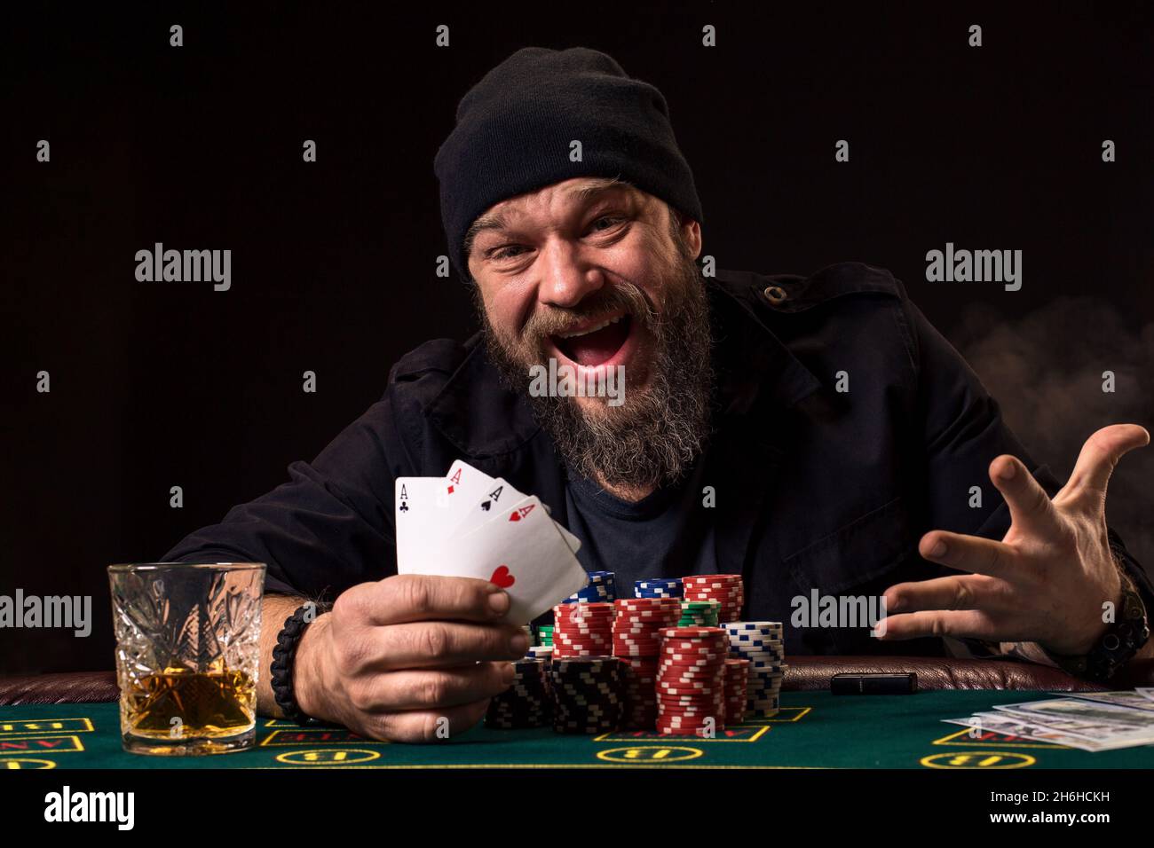 Bearded man drinking whisky while playing poker Stock Photo