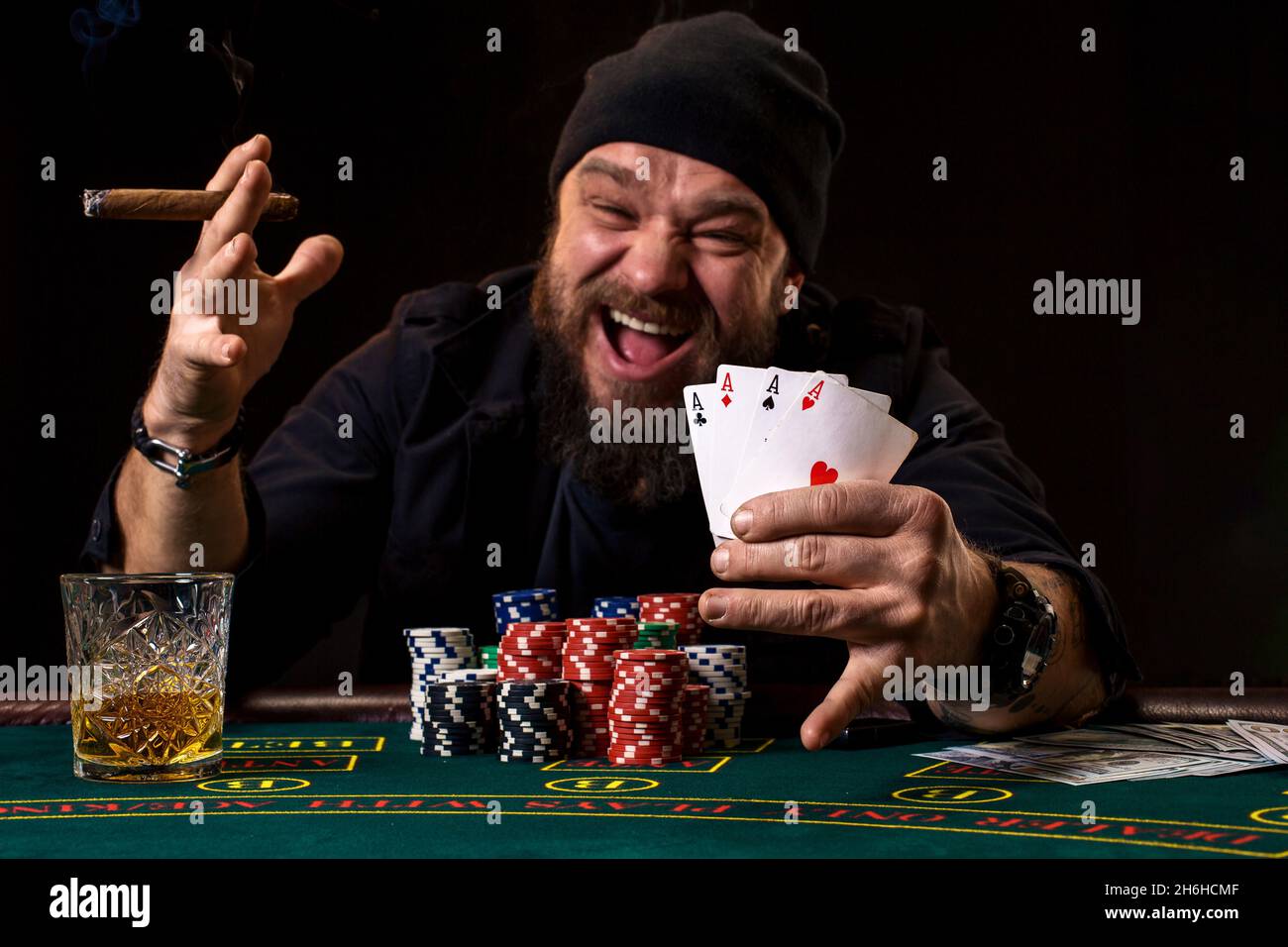 Bearded man drinking whisky and smoking a cigar while playing poker Stock Photo