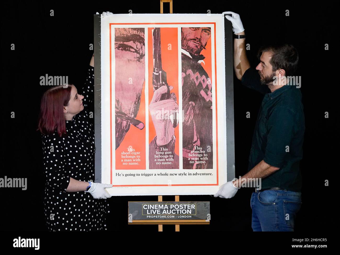 Prop store employees adjust a US Advance One-Sheet style BA poster for the 1967 film 'A Fistful of Dollars' at their auction house in Rickmansworth, Hertfordshire. It is estimated to sell between £4,000 - £6,000 in the forthcoming cinema poster auction by the Prop Store. Picture date: Thursday November 4, 2021. Stock Photo