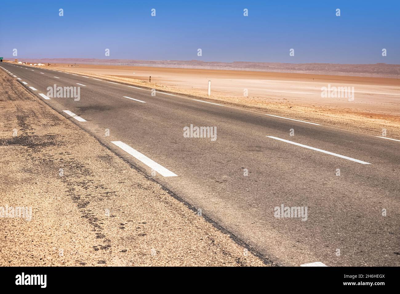 An asphalt road that runs along the Sahara Desert. Sahara Desert, Tunisia Stock Photo
