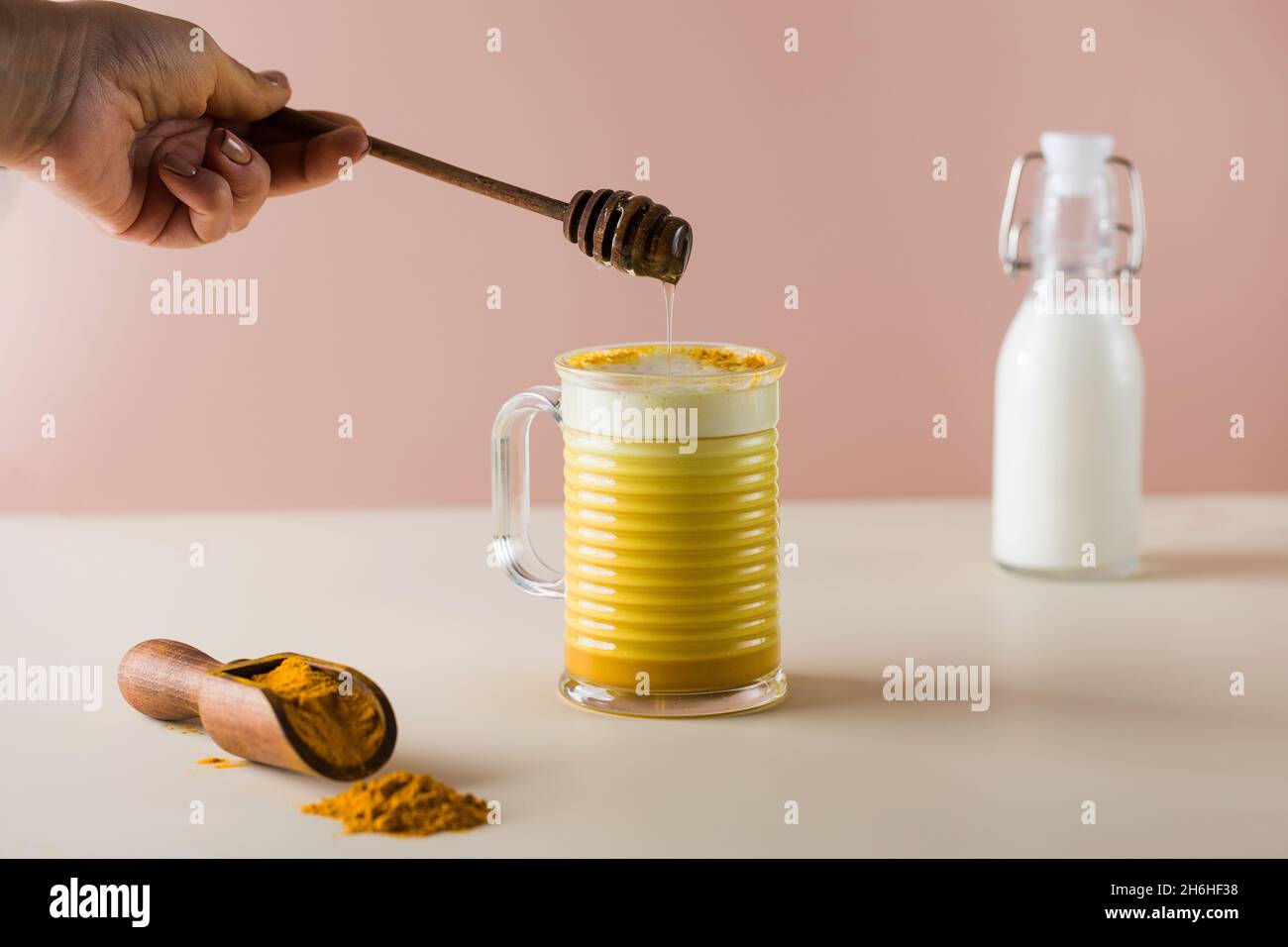 A drop of honey drips into a latte turmeric mug. Moon milk for better