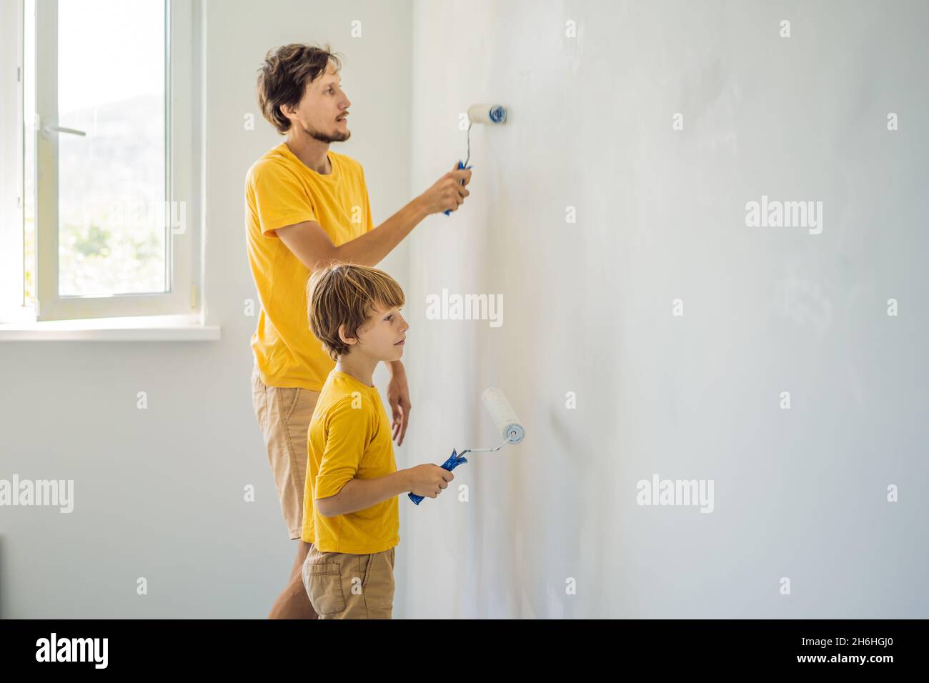 Father and son painting a wall in their home do it in the course of ...