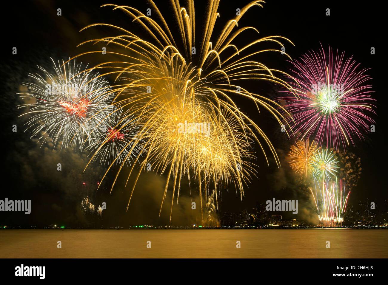 Colorful fireworks celebration and the city night light background with sea view. Stock Photo