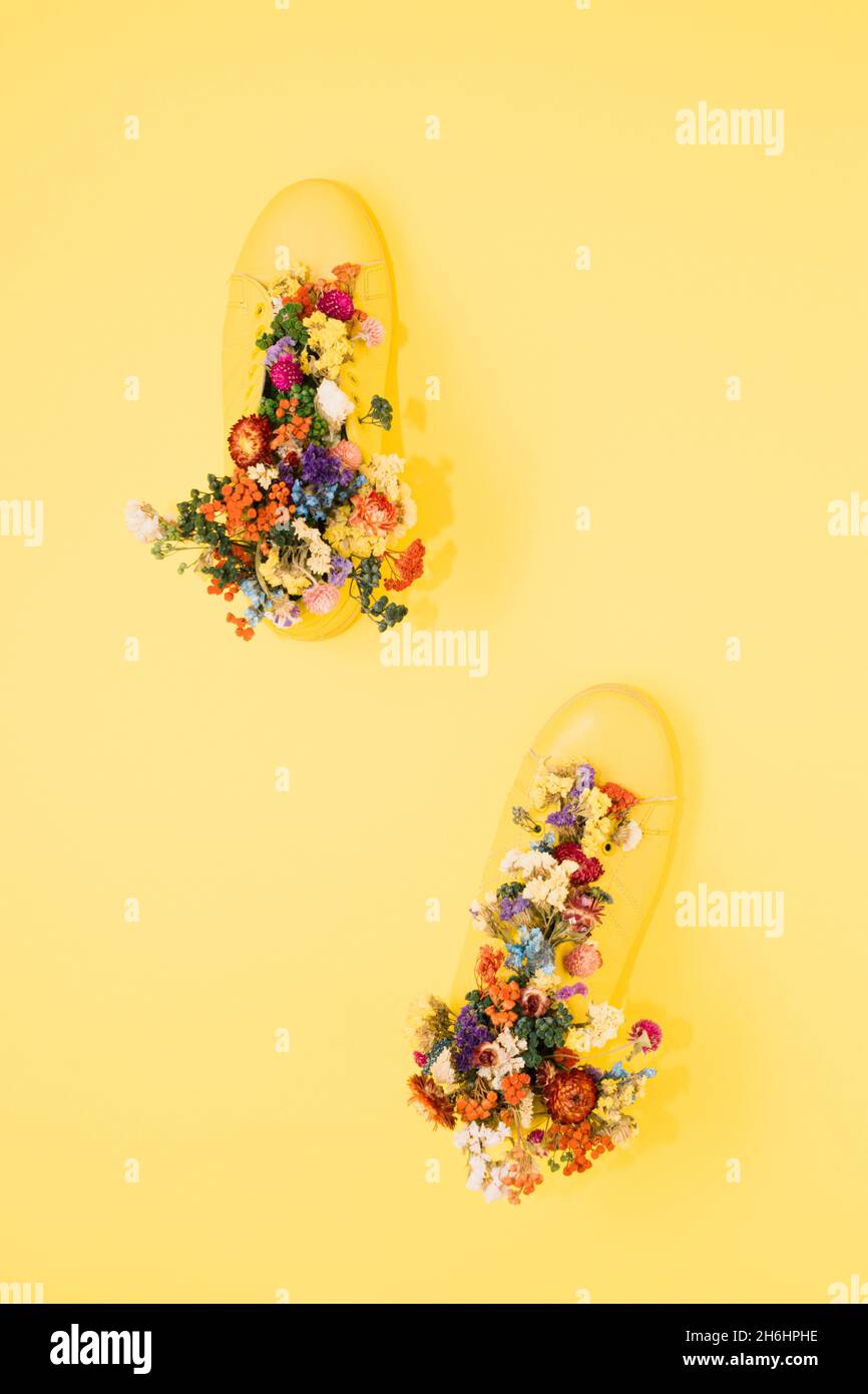 Top view of yellow boots decorated with colorful flowers on the yellow surface - space for text Stock Photo