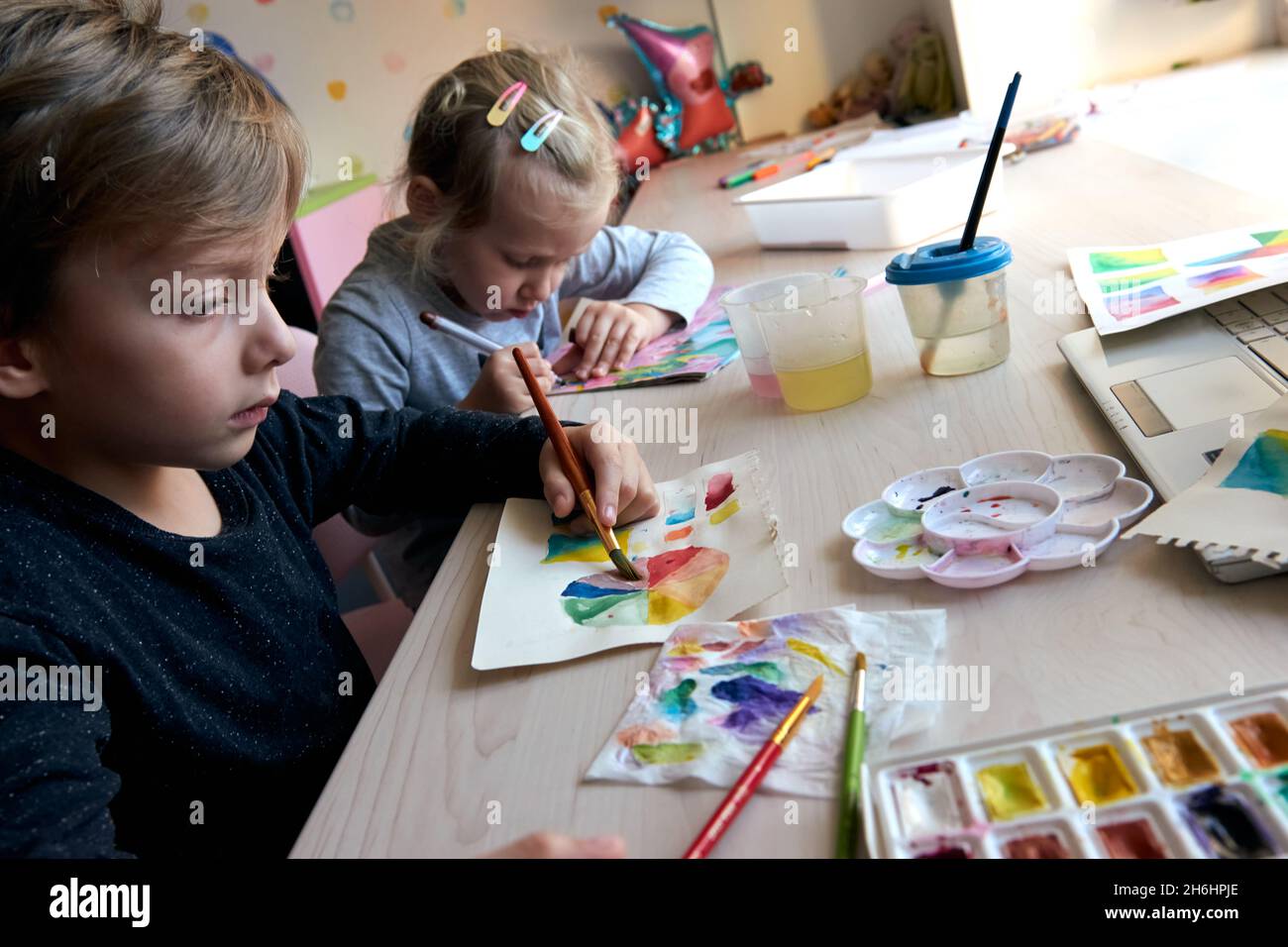 Children painting pictures with watercolor paints during art lesson ...