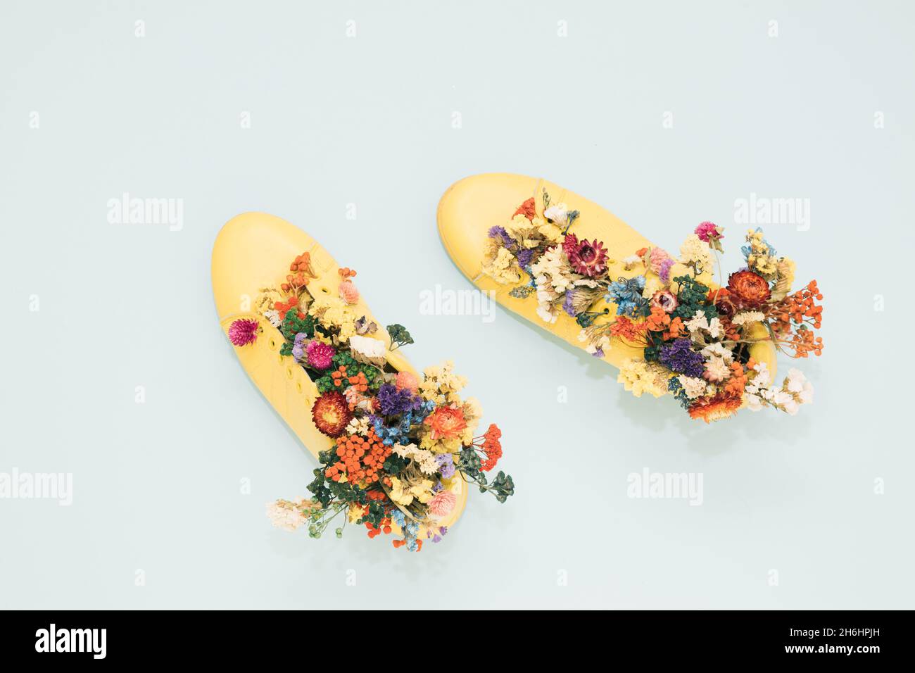 Top view of yellow boots decorated with colorful flowers on the gray surface - space for text Stock Photo