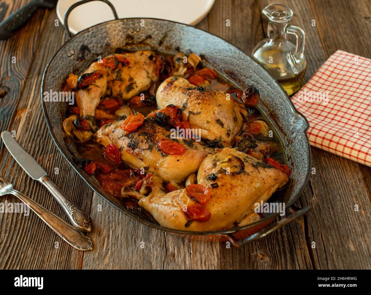 rustic chicken dish with vegetables served in a old fashioned roasting pan on wooden table Stock Photo