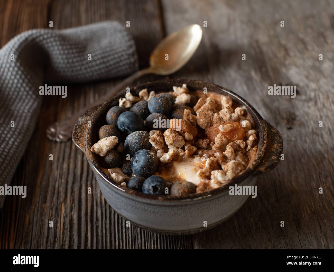 High protein breakfast with greek yogurt, pureed pumpkin, smashed brown rice cakes, blueberries and cinnamon. Served isolated on wooden table. Stock Photo