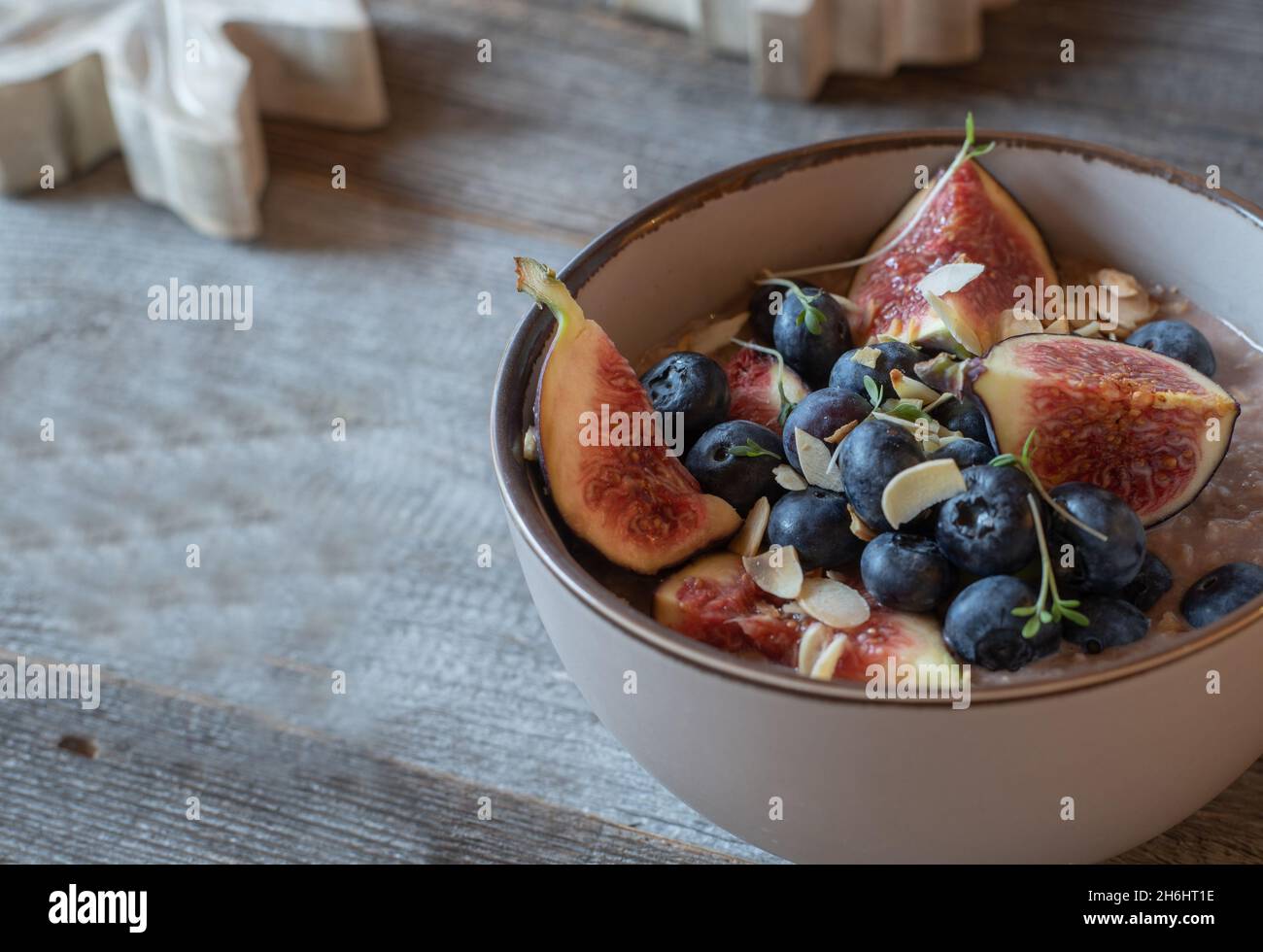 Fitness breakfast bowl with a porridge made with chocolate whey protein, roasted almonds, figs and fresh blueberries. Stock Photo