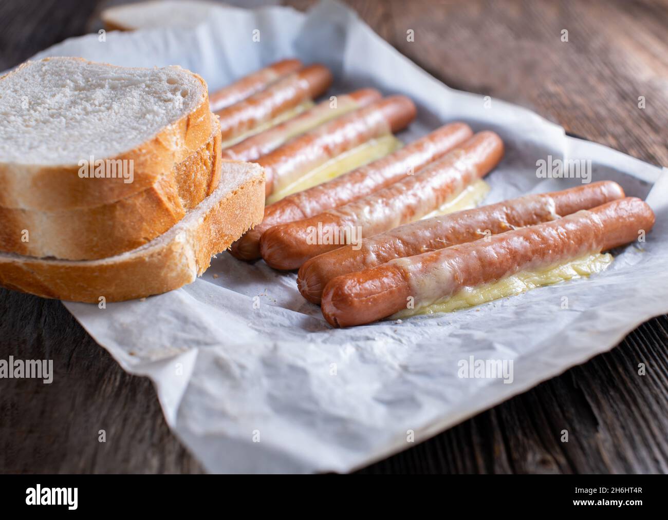 Sausages with melted cheese and white bread - unhealthy eating Stock Photo