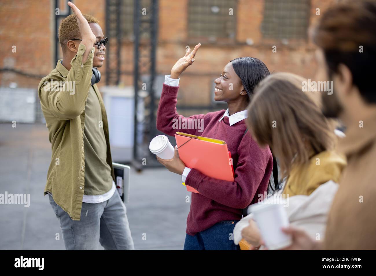 Black girl and guy hold hands near their friends Stock Photo - Alamy