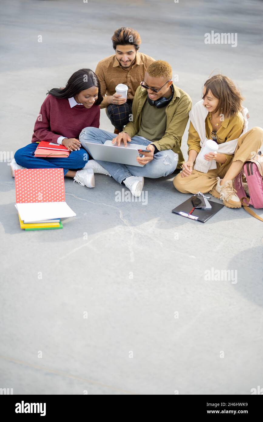 Students watching something on laptop on asphalt Stock Photo
