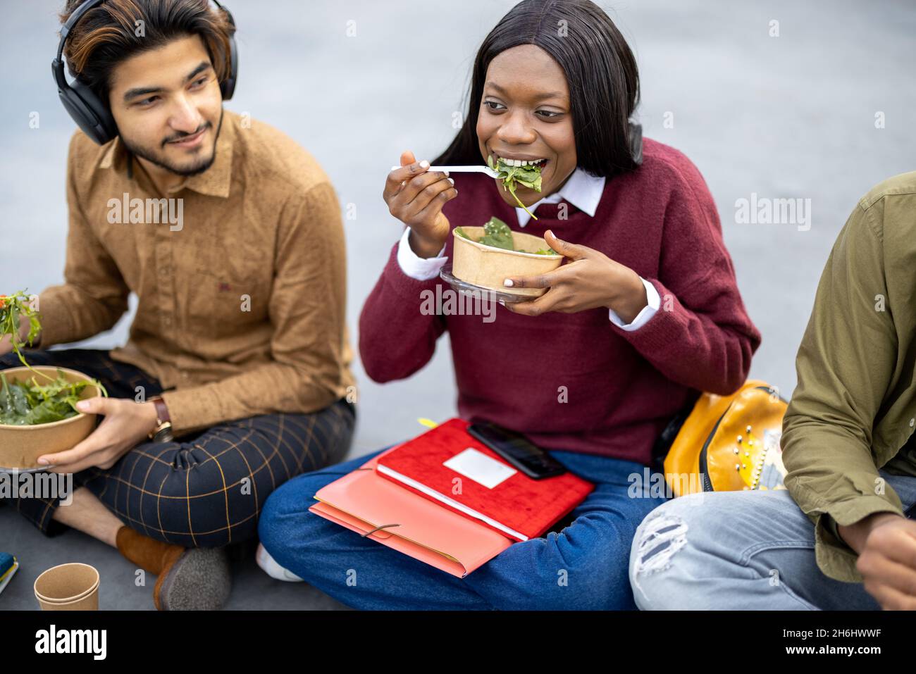 Students eating salad during lunch on asphalt Stock Photo