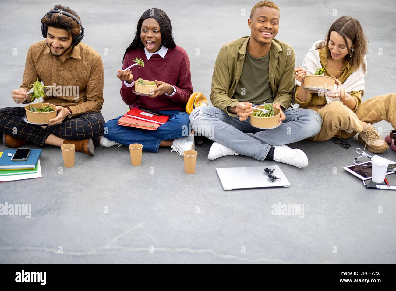 Students eating salad during lunch on asphalt Stock Photo
