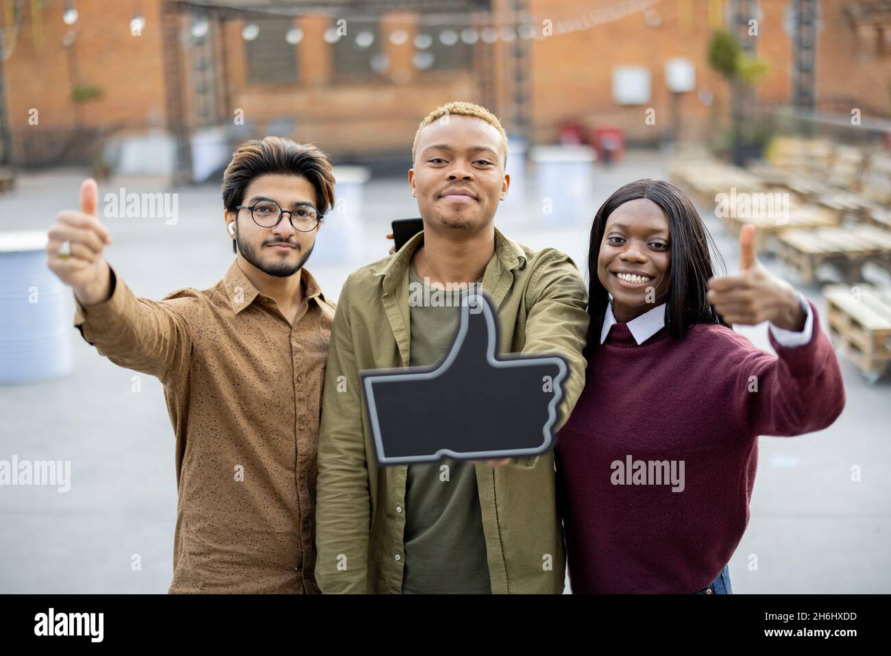 Guy hold phone and show thumb up with friends Stock Photo