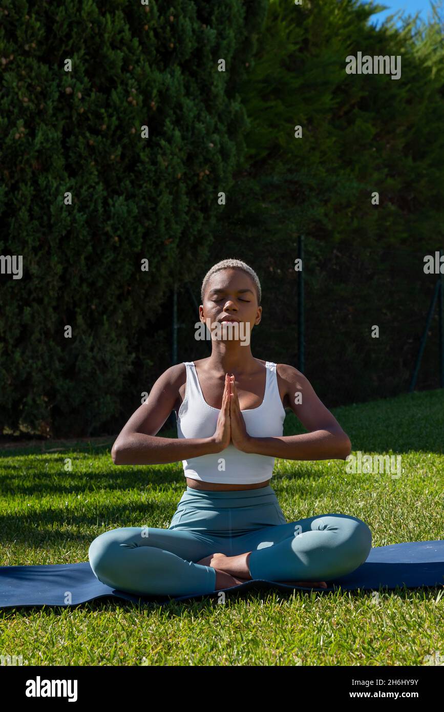 Tranquil African American female with short hair sitting in Lotus pose ...