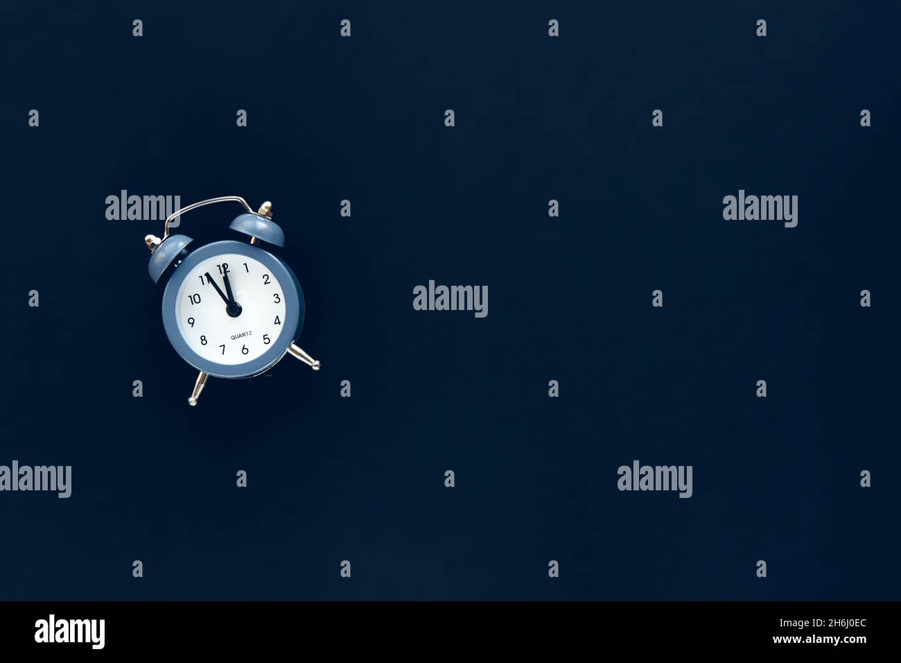 Blue vintage alarm clock shows 12 o'clock isolated on dark background