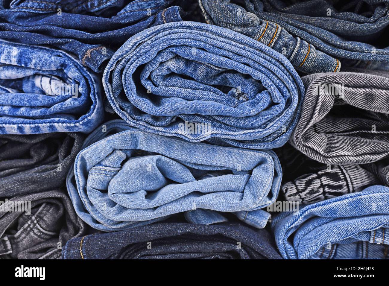 Different colored jeans pants rolled up in pile Stock Photo
