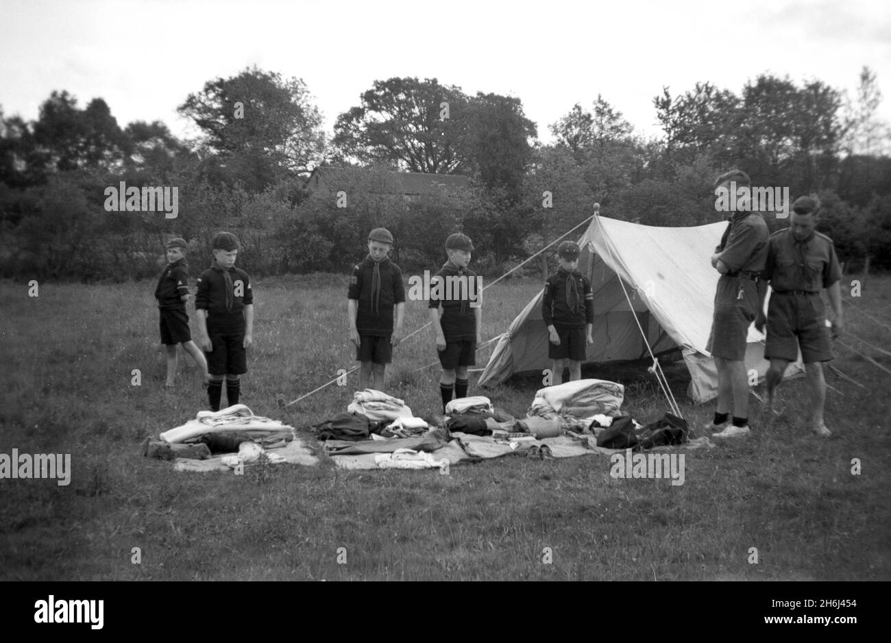 1938, outside in a field by their tent, a kit inspection of cub scouts taking place, Felbridge, Surrey, England, UK.  Scouting began in 1908, after British Army Officer General Robert Baden-Powell held an experimental camp on Brownsea Island, Poole Harbour, the previous summer. Around 20 boys attended and were taught a range of outdoor skills, including tracking, firelighting, making shelters out of branches, knotting, cooking, health and sanitation, life-saving and First Aid. In 1914 Young Scouts or Wolf Cubs were launched for boys aged nine. At the age of 12, they could become boy scouts. Stock Photo