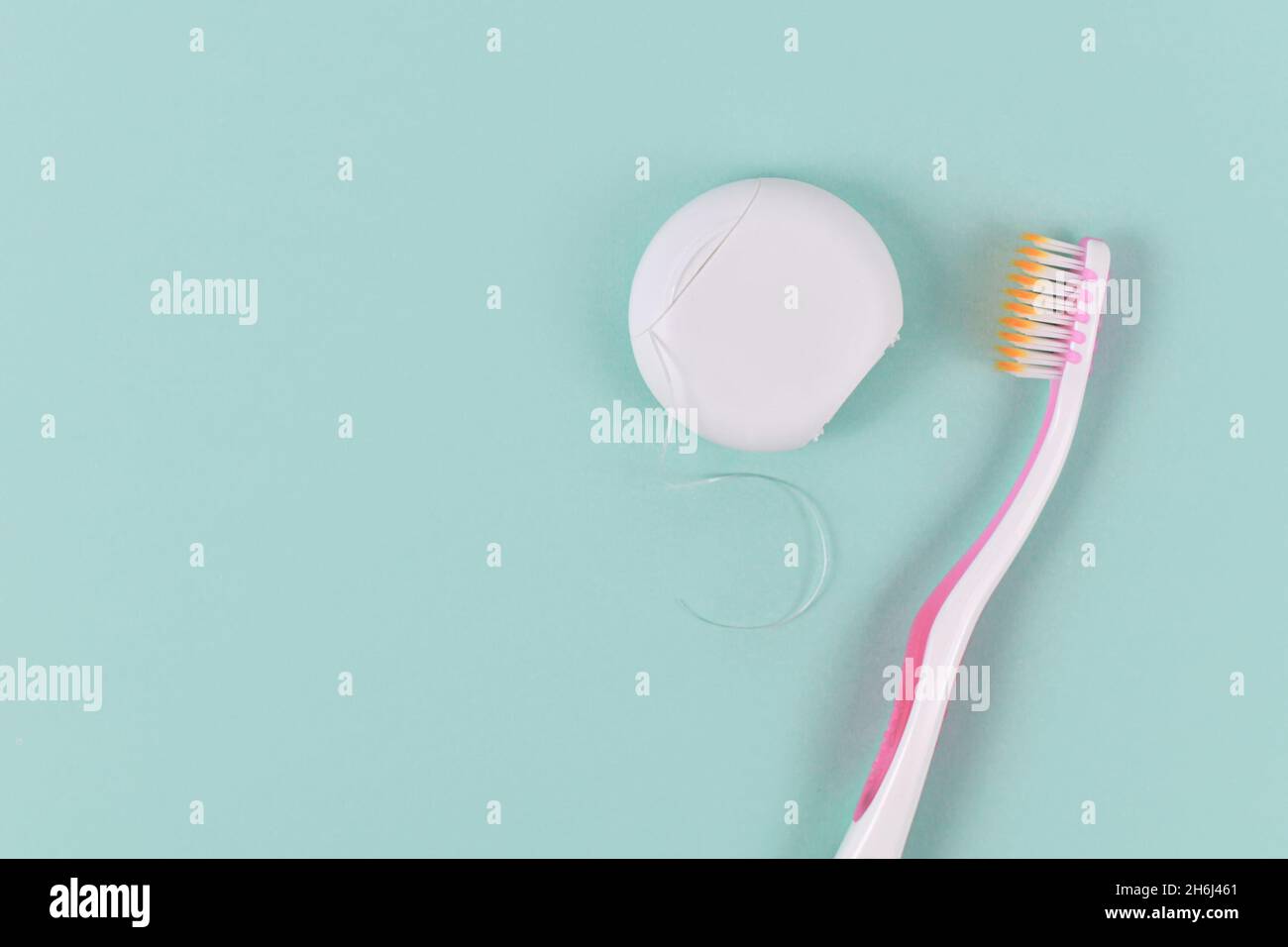 Dental floss and tooth brush on side of green background with copy space Stock Photo