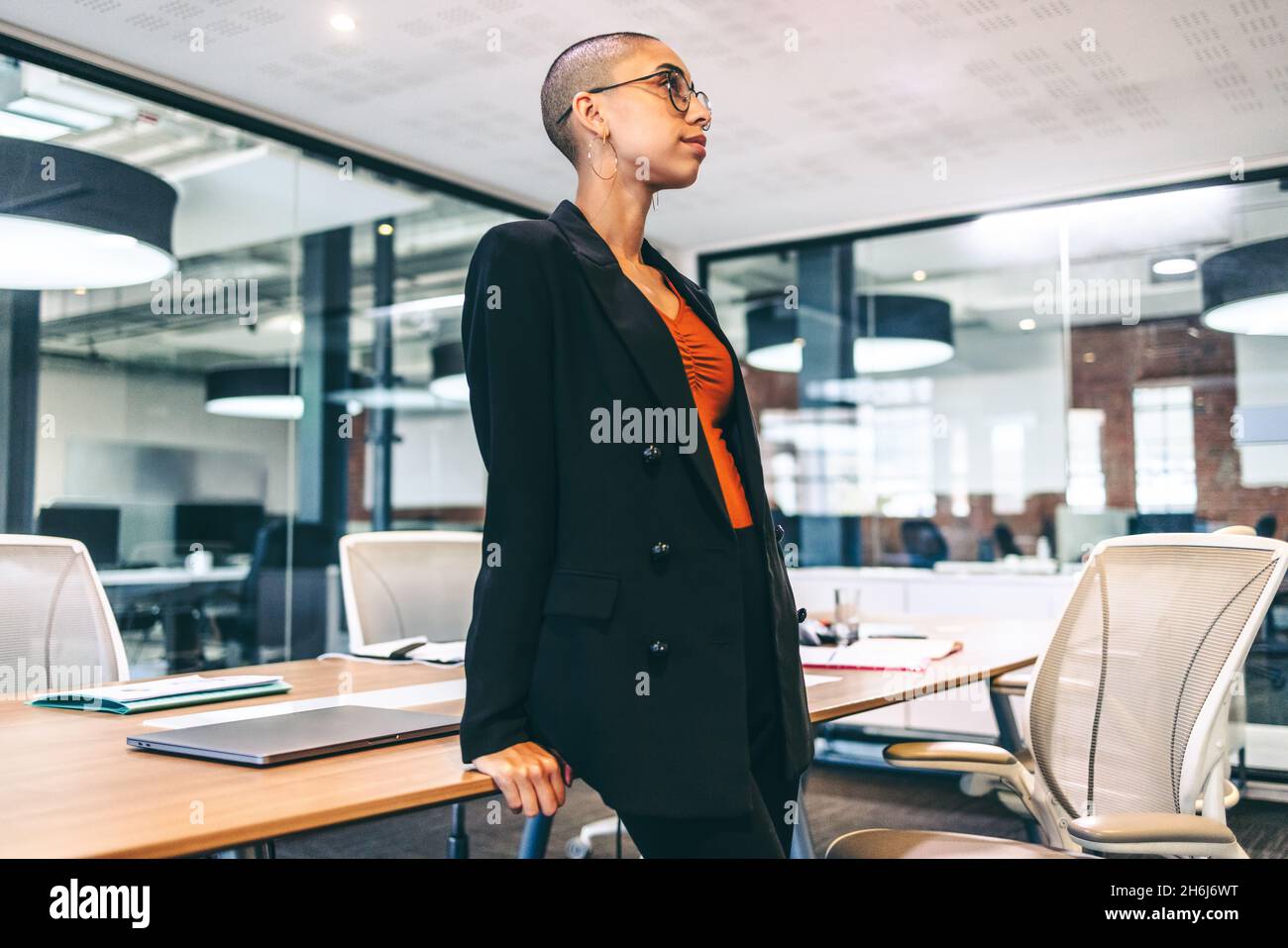 Female entrepreneur looking away thoughtfully in a boardroom. Confident young businesswoman standing alone in a modern workplace. Young businesswoman Stock Photo