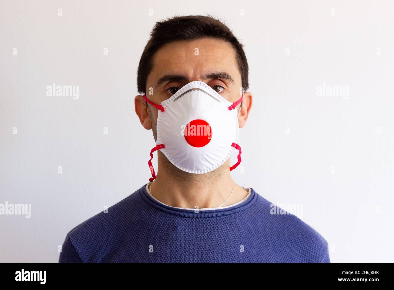 Portrait of young man wearing face mask with red cap in the middle. Patient with air breathing protection equipment. Pandemic, coronavirus concepts Stock Photo