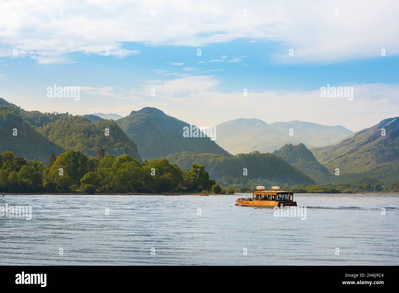 Derwent Water, view on a summer morning of a ferry boat cruising Derwent Water with a view of Borrowdale High Fells in the distance, Lake District, UK Stock Photo