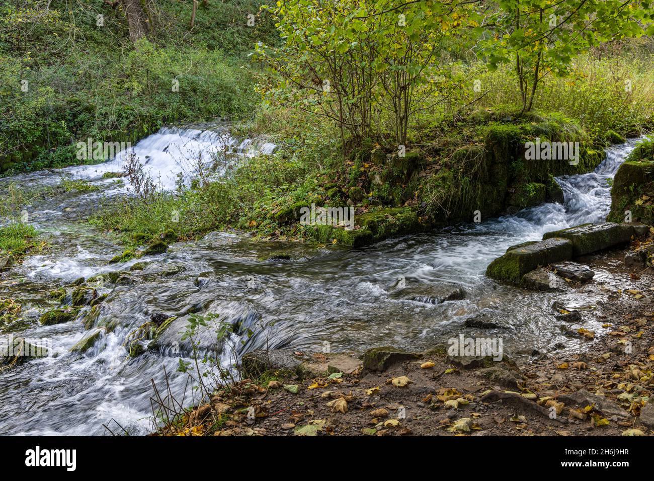 A picturesque weir over limestone rocks near the Fishponds, River Lathkill, Lathkill Dale, Peak District National Park, Derbyshire, England. Stock Photo
