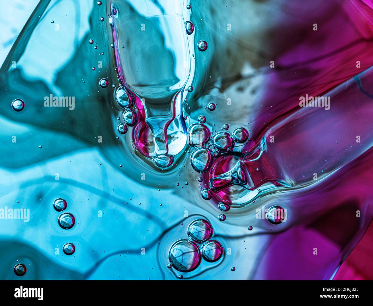Liquid serum and dropper on blue and pink background with leaf texture. Front view. Stock Photo
