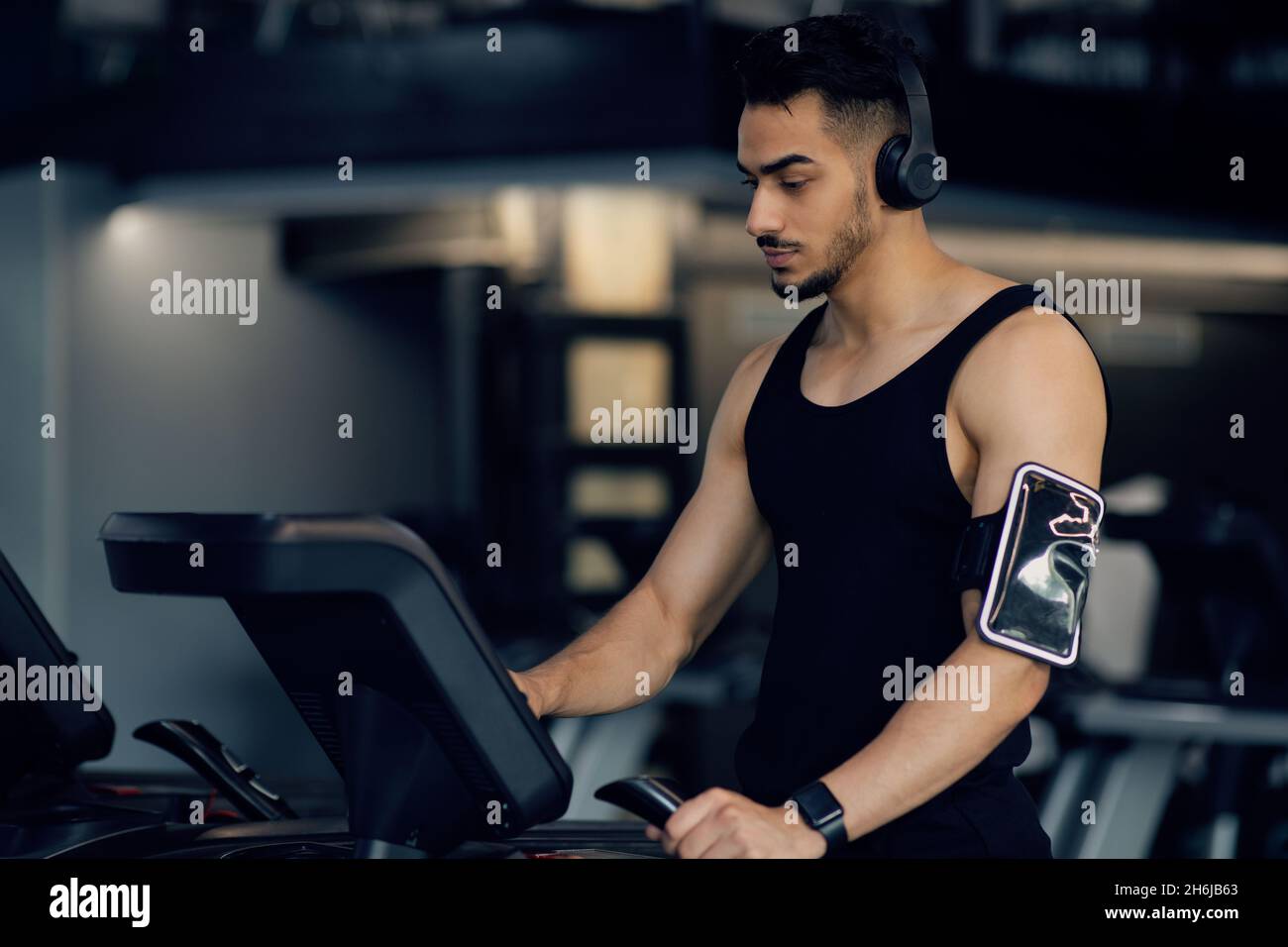 Sport Training. Young Arab Man Wearing Wireless Headphones Using