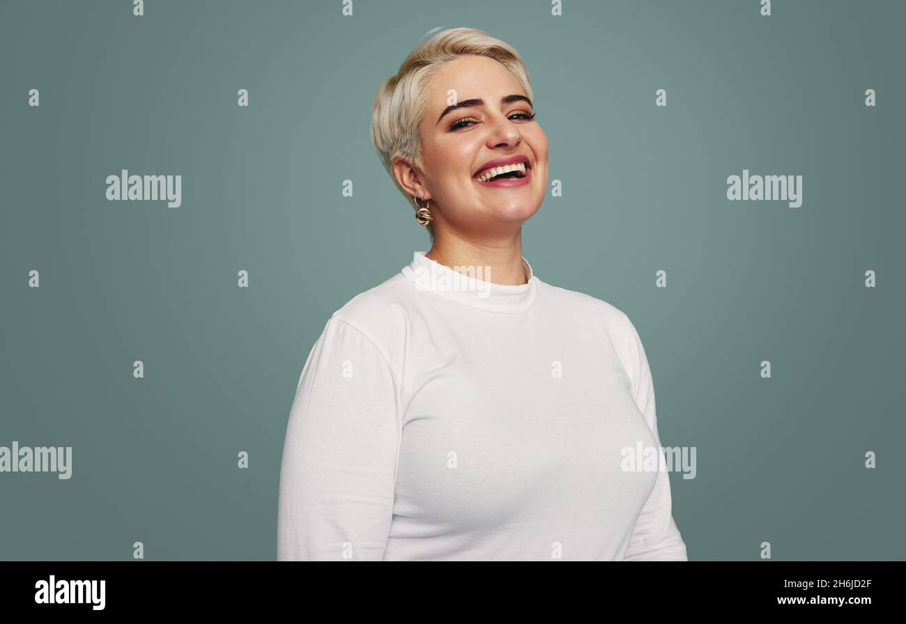 Feeling happy in the studio. Cheerful mid-adult woman smiling at the camera while standing alone against a studio background. Fashionable blonde woman Stock Photo