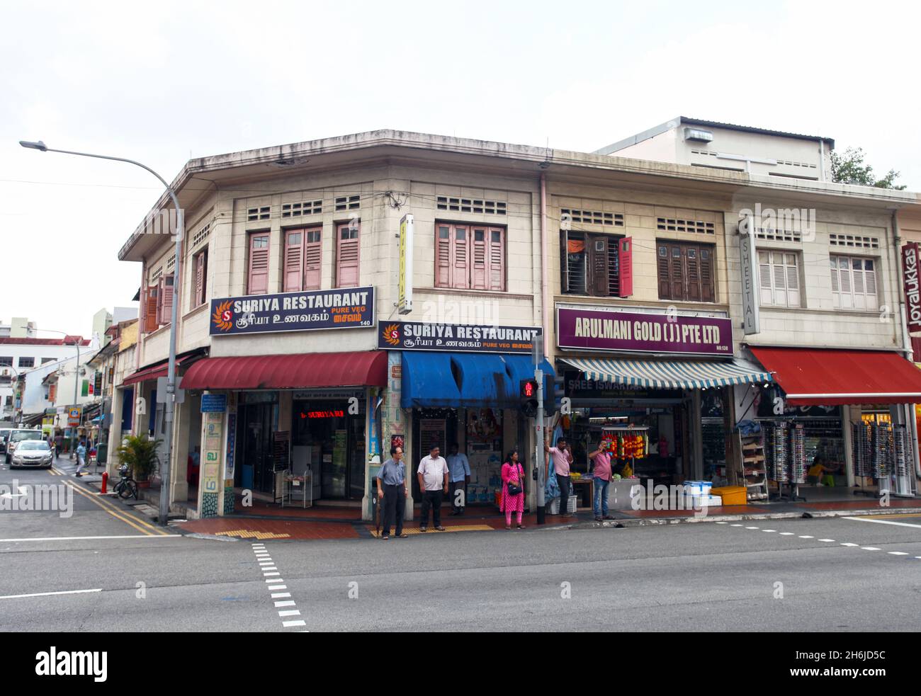 A row of shophouses on Serangoon Road in Little India, Singapore with Suriya Restaurant and Arulmani Gold and people waiting at a pedestrian crossing. Stock Photo