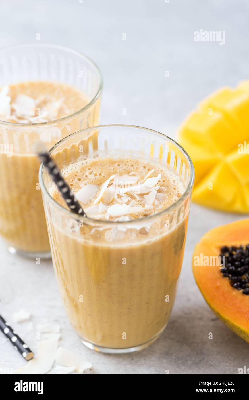 Vegan Tropical smoothie of mango, coconut and papaya in glass, closeup view Stock Photo
