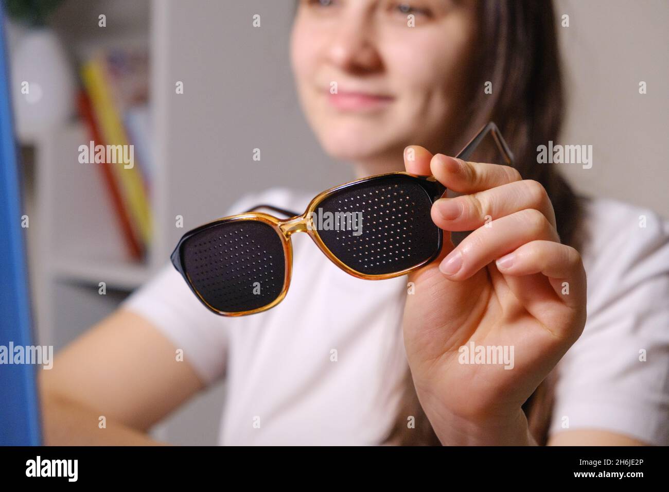 A woman holds perforation glasses to correct visual impairment Stock