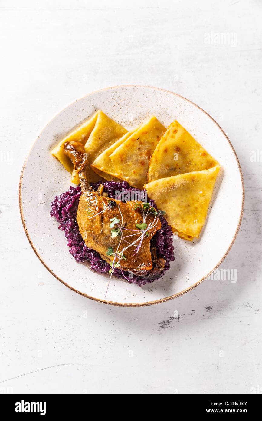 Portion of duck leg with red cabbage and potato pancakes - Top of view. Stock Photo